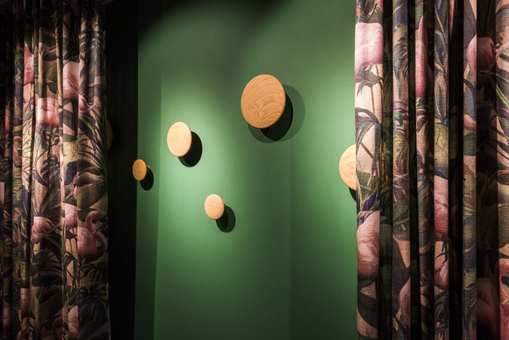 Garderobenhaken aus Holz, grüne Wand, Stadtwohnug, Flamingo, Vorhänge